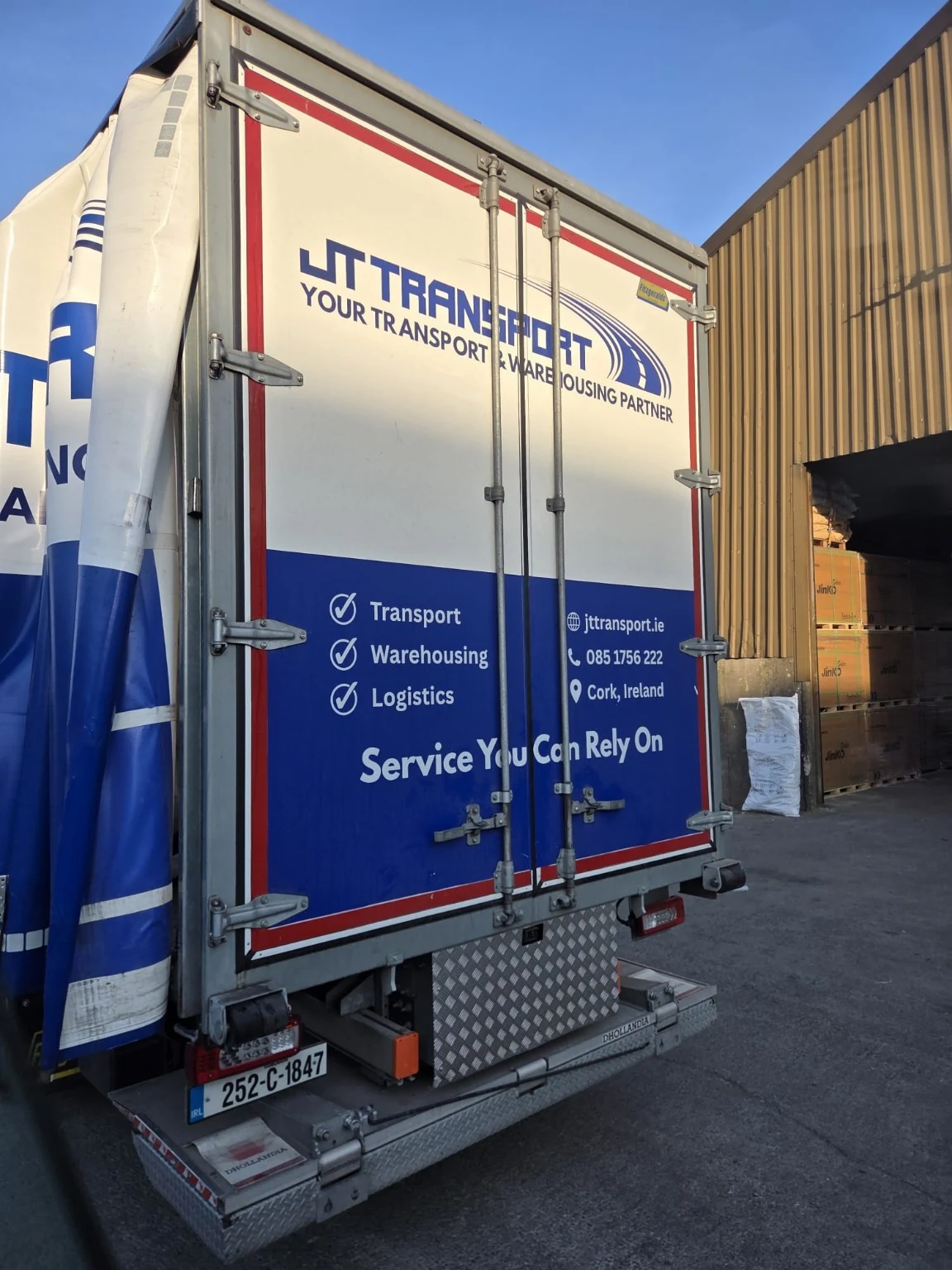 JT vehicle rear-door branding beside stored goods.